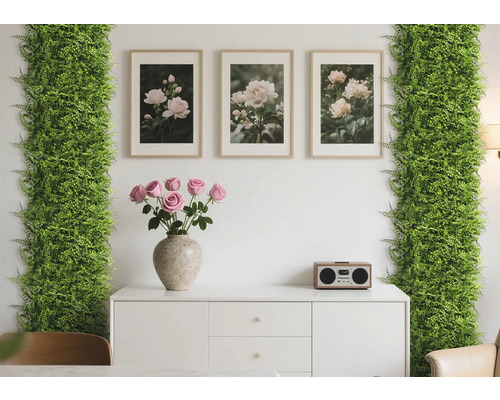 Scène décorative avec des plantes artificielles, des cadres photo, des roses et une commode