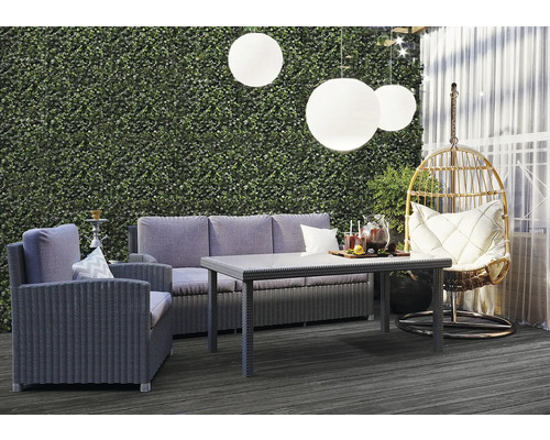 Salon de jardin avec canapé, fauteuil, table et panier suspendu sur une terrasse avec un mur végétal en arrière-plan