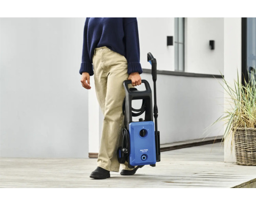 Eine Person trägt einen Nilfisk Hochdruckreiniger.