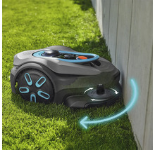 Rasenmähroboter beim Mähen entlang einer Wand auf Gras