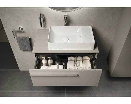 Meuble-lavabo de salle de bains avec tiroir ouvert, avec des serviettes et des accessoires de bain, au-dessus du meuble-lavabo se trouve un lavabo rectangulaire