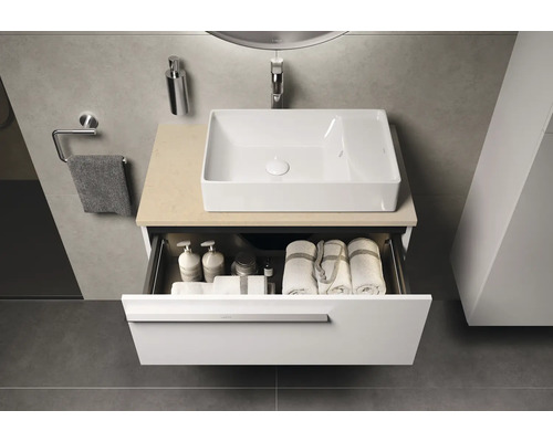 Meuble-lavabo de salle de bain avec tiroir ouvert, lavabo, serviettes et produits de soin