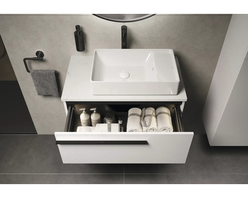 Meuble-lavabo avec tiroir ouvert, serviettes et produits de soin dans une salle de bains