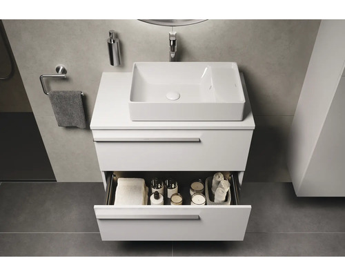 Salle de bains moderne avec meuble sous-vasque, vasque à poser et tiroir ouvert pour ranger les articles de toilette.