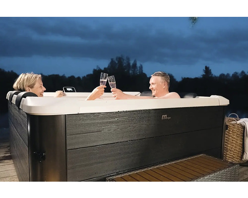 Ein Paar stößt in einem Whirlpool im Freien mit Sekt an