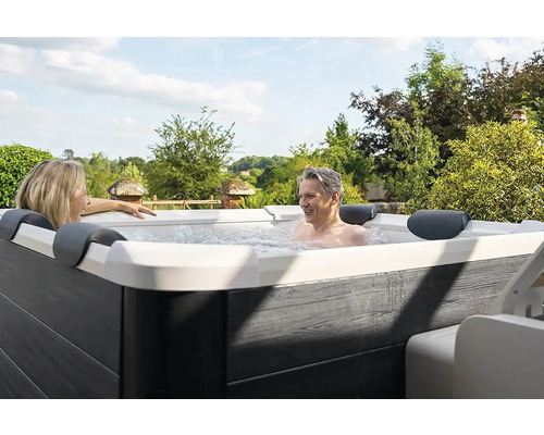 Zwei Personen entspannen in einem Whirlpool im Freien.