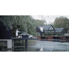 Szene mit einem Whirlpool auf einer Plattform am See und einem Haus im Hintergrund