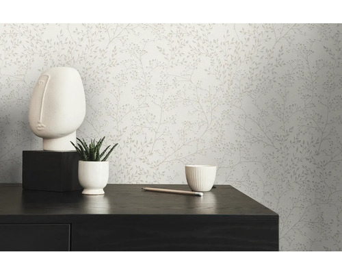 Szene mit floral gemusterter Tapete, einer weißen Gesichts-Skulptur, einer Sukkulente im Topf und einem Stift auf einem dunklen Tisch.