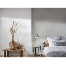 Helles Schlafzimmer mit Dekorationselementen und einer Nachttischlampe auf einem Hocker