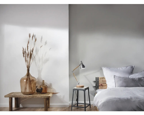 Helles Schlafzimmer mit Dekorationselementen und einer Nachttischlampe auf einem Hocker