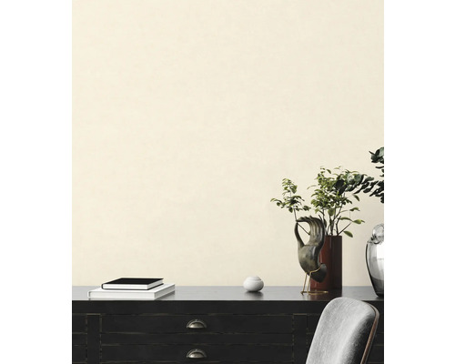 Dekorative Inneneinrichtung mit Kommode, Büchern, Pflanzen und Skulpturen vor einer Wand