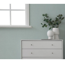 Kommode mit Dekorationsgegenständen vor einer Wand neben einem Fenster