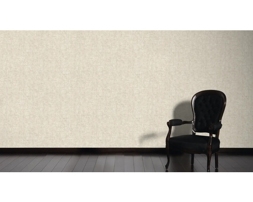 Mur clair avec papier peint textile et fauteuil noir sur parquet foncé.