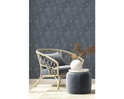 Szene mit Rattan-Sessel, Hocker und floral gemusterter Tapete