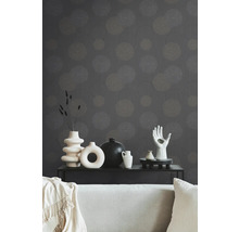 Dekoratives Wohnzimmer mit gemusterter Tapete, Couch und verschiedenen Vasen auf einem schwarzen Tisch