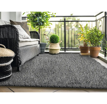 Scène de balcon avec canapé en rotin, plantes et gazon synthétique gris