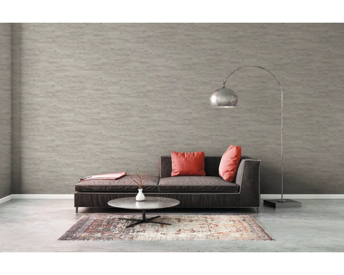 Wohnzimmer mit Sofa, Teppich, Tisch und Stehlampe vor einer strukturierten Tapete.