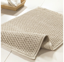 Tapis de bain beige sur carrelage de salle de bain