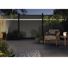 Jardin avec clôture d'intimité éclairée, fauteuil et lampe de table de nuit