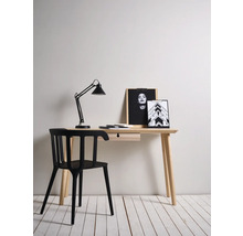 Bureau avec lampe, chaise et objets de décoration dans une pièce lumineuse.