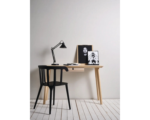 Bureau avec lampe, chaise et objets de décoration dans une pièce lumineuse.