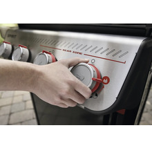 Une personne utilise un bouton rotatif sur un gril à gaz