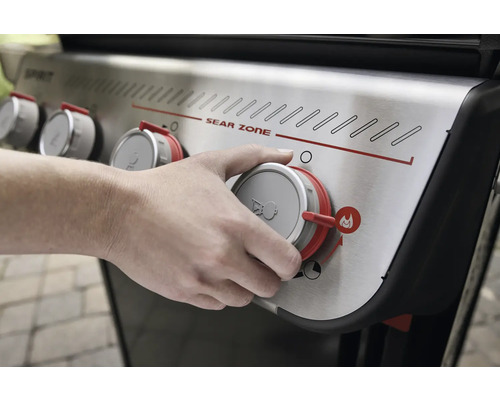 Une personne utilise un bouton rotatif sur un gril à gaz