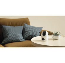 Caméra de surveillance Imou sur une table à côté d'une plante d'intérieur et d'un canapé