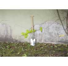 Bêche avec manche en bois contre un mur