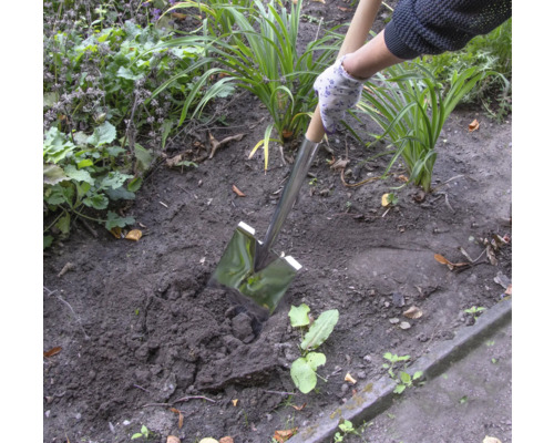 Une personne utilise une bêche pour creuser dans le jardin.