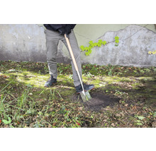 Une personne creuse dans le jardin avec une bêche