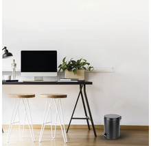 Bureau avec bureau, chaises et une poubelle à pédale ronde.