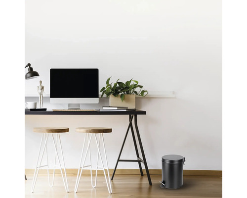 Bureau avec bureau, chaises et une poubelle à pédale ronde.
