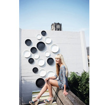 Mur décoratif avec assiettes décoratives à l'extérieur avec une femme assise sur un banc