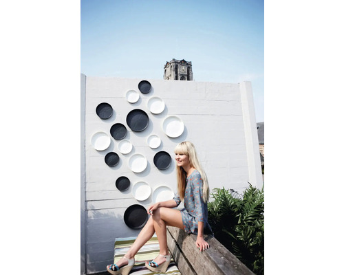 Mur décoratif avec assiettes décoratives à l'extérieur avec une femme assise sur un banc