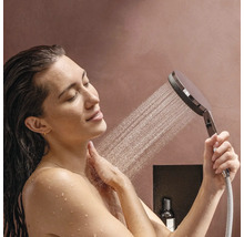 Eine Frau benutzt eine Handbrause unter der Dusche.