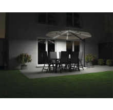 Jardin avec table à manger, chaises et parasol lumineux le soir