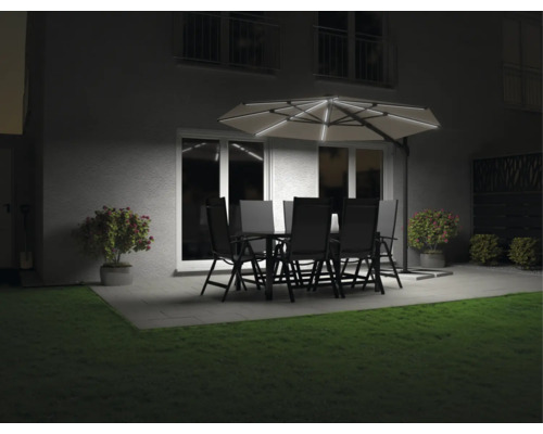 Jardin avec table à manger, chaises et parasol lumineux le soir