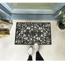 Paillasson en caoutchouc avec motif décoratif devant une porte d'entrée