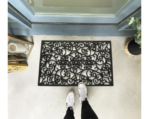 Paillasson en caoutchouc avec motif décoratif devant une porte d'entrée