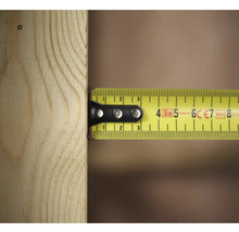 Un mètre à ruban jaune mesure un morceau de bois