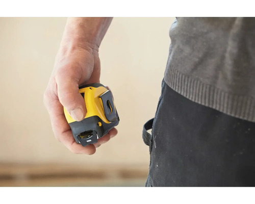 Main tenant un mètre ruban jaune et noir.