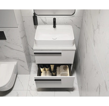 Salle de bain moderne avec meuble sous-lavabo blanc, tiroir ouvert et carrelage en marbre