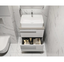 Salle de bains moderne avec meuble sous-lavabo blanc et tiroir ouvert pour les accessoires de bain.