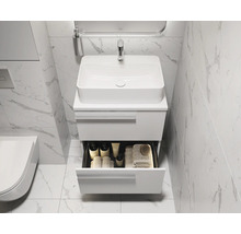 Salle de bains moderne avec lavabo, meuble sous-lavabo et tiroir ouvert pour les accessoires de salle de bains