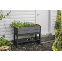 Jardinière surélevée en plastique avec étagère devant un mur de maison