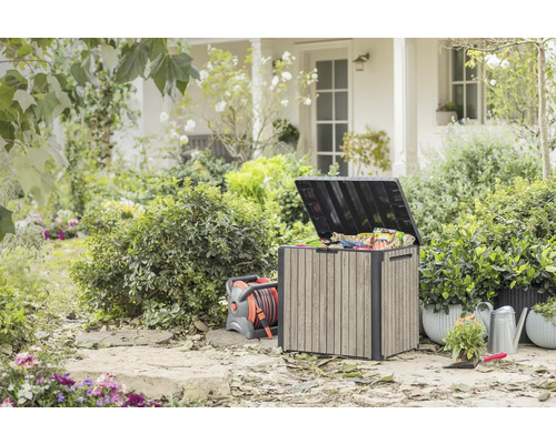 Garten im Freien mit Aufbewahrungsbox, Schlauchaufroller, Giesskanne und Pflanzen