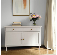 Dekoratives Sideboard mit Schubladen und Türen, darauf Bücher und ein Blumenstrauß in einer Vase, darüber ein gerahmtes Bild.