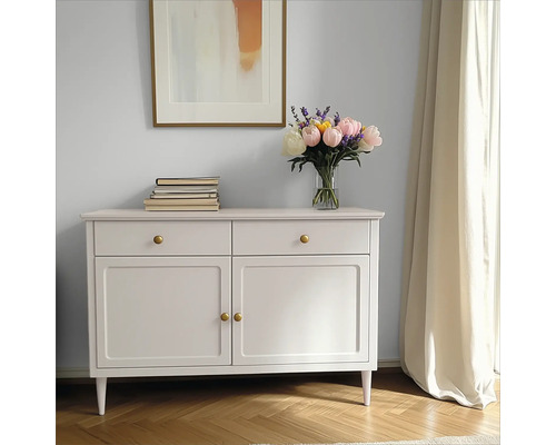 Dekoratives Sideboard mit Schubladen und Türen, darauf Bücher und ein Blumenstrauß in einer Vase, darüber ein gerahmtes Bild.