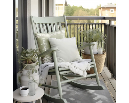 Balkonszene mit Schaukelstuhl, Kissen, Decke, Pflanzen und Beistelltisch für entspannte Momente im Freien